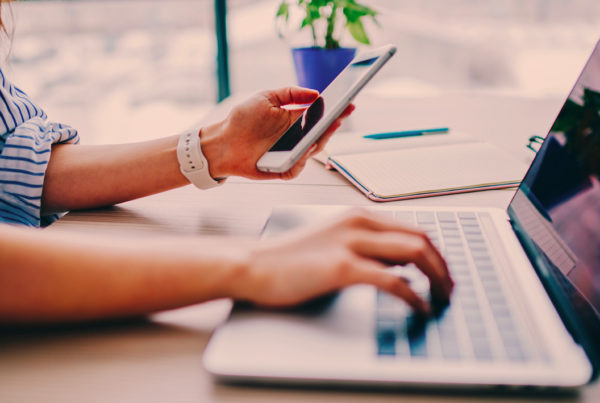 Femme en train de consulter son téléphone et son ordinateur pour communiquer sur sa démarche innovation